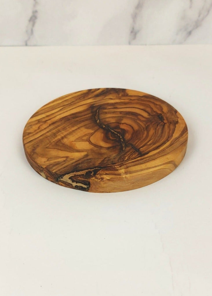 A circle olive wood coaster, featuring a unique natural grain pattern