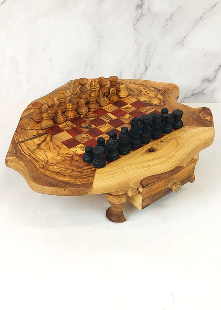 an olive wood chess board with legs and drawers featuring red and brown squares, paired with handcrafted black and brown olive wood chess pieces