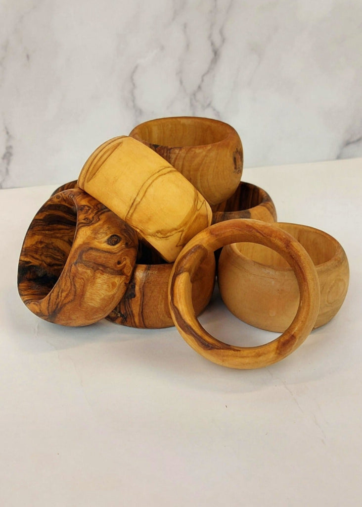 A stack of olive wood napkin rings, each featuring unique natural wood grain patterns