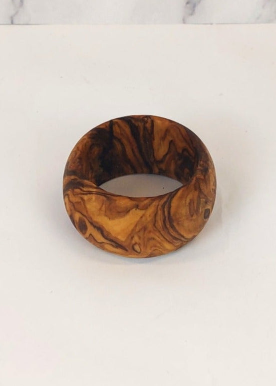 A olive wood napkin ring, featuring a unique natural wood grain pattern