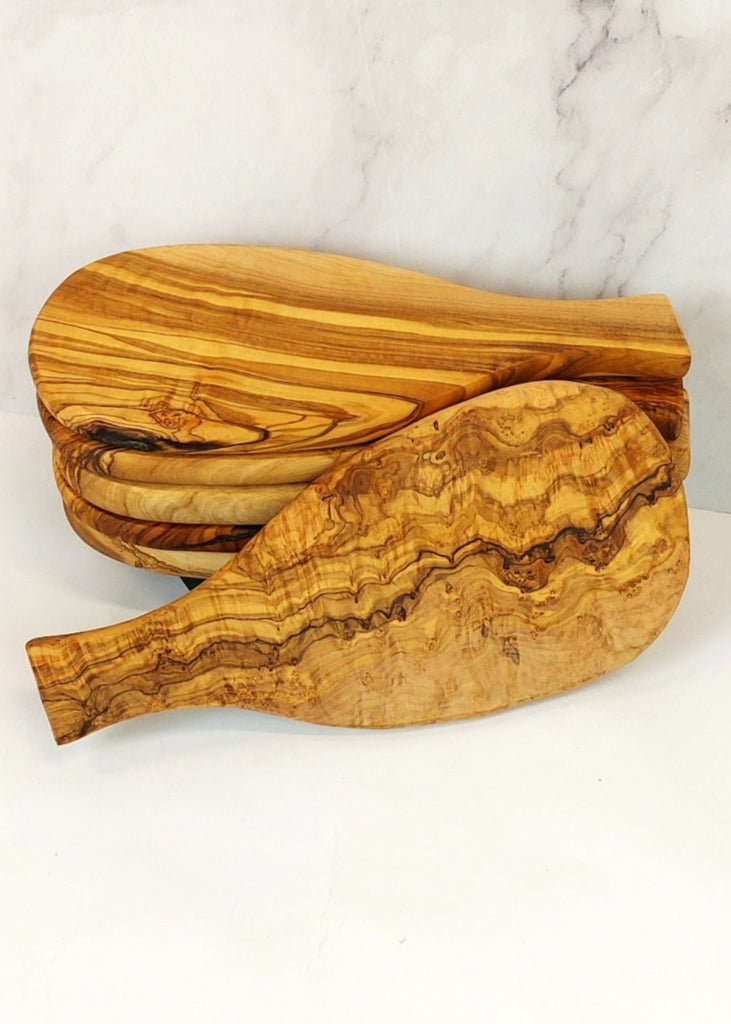 A neatly stacked set of six small non-rustic olive wood cheese boards with smooth, polished surfaces