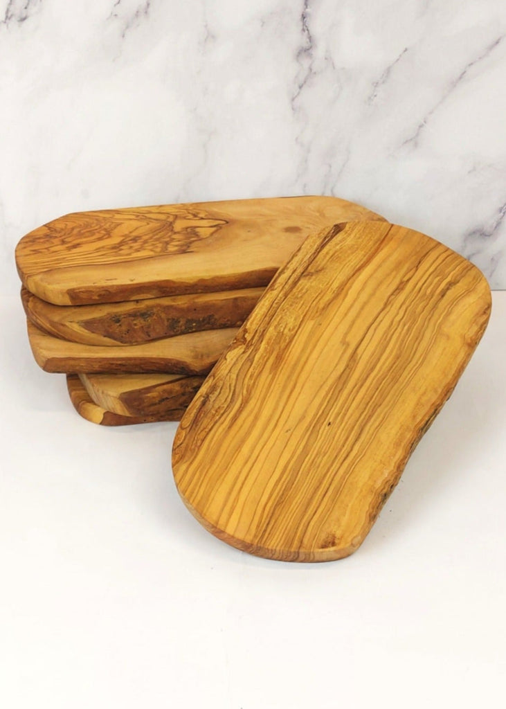 A stack of six rustic live edge cheese boards, each showcasing unique natural wood grain patterns