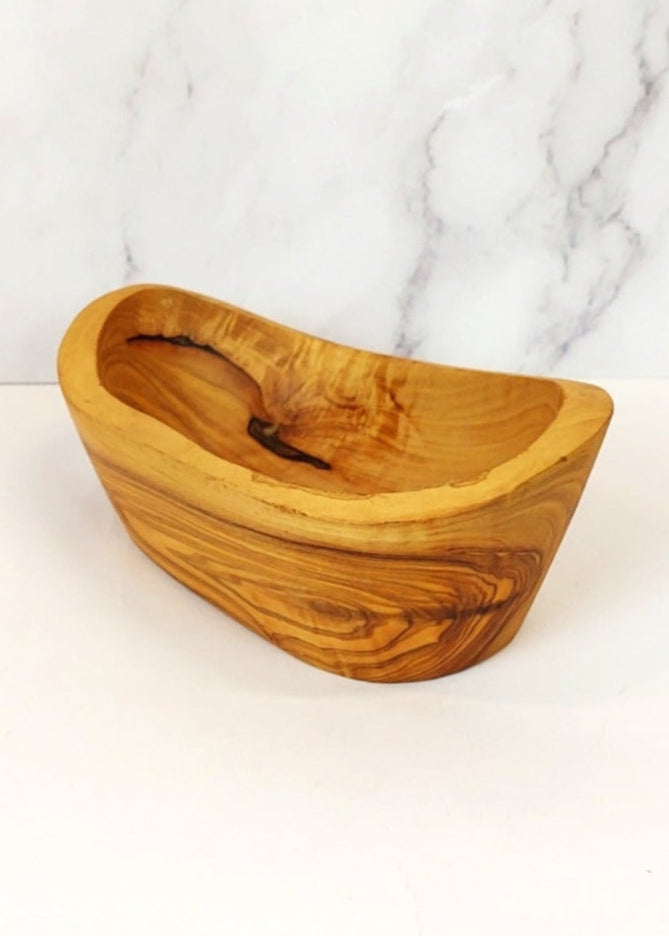 A small rustic oval serving dish handcrafted from olive wood, with a unique natural grain pattern